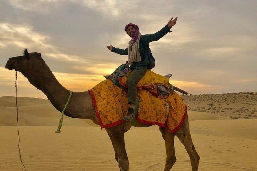 A person riding a camel in a desert with sand dunes in the background. 4