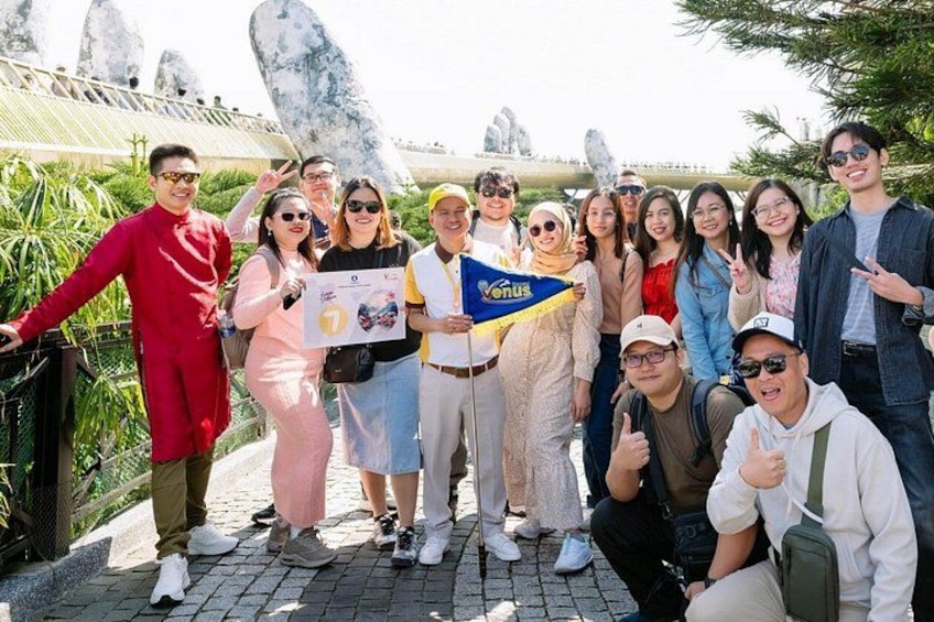 A group of people posing in front of a rocky landscape with large boulders and a bridge in the background. 2