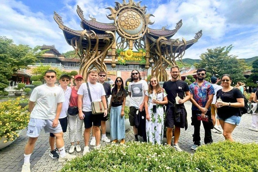 Un grupo de personas frente a una estructura arquitectónica tradicional con detalles ornamentales. 4