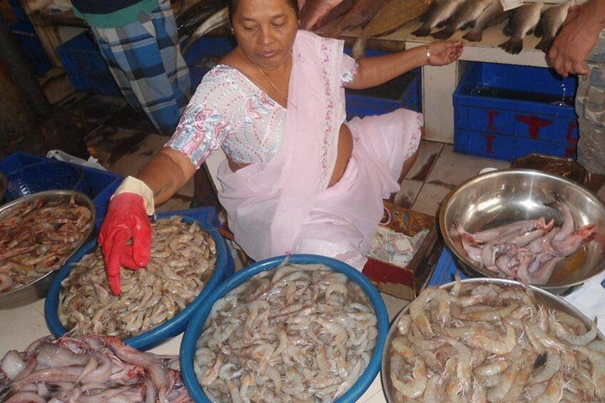 A person sorting seafood in bowls at a market. 1