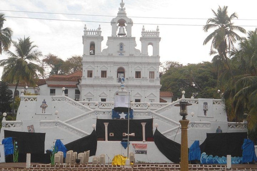 A white colonial-style church with a bell tower, surrounded by palm trees. 4