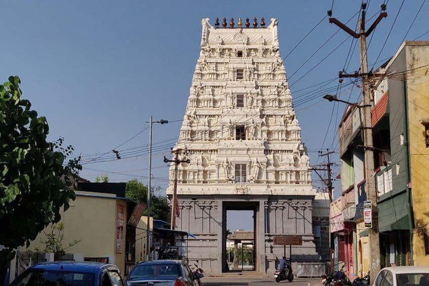 A temple with intricate carvings, surrounded by buildings and vehicles. 2
