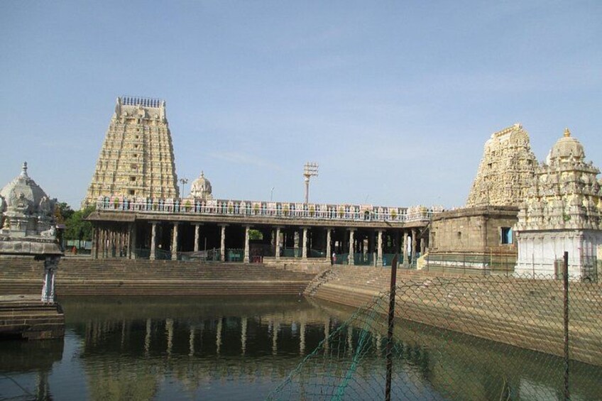 Un templo con un gran gopuram, un cuerpo de agua al frente y un santuario más pequeño a la derecha. 3