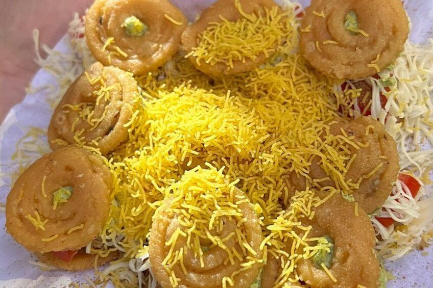 A plate of food with sev, a type of Indian snack, and a fried item. 3