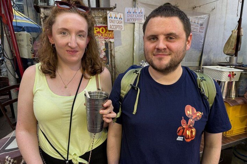Two people standing in an outdoor setting with a sign that reads 'Only cash accepted.' 2