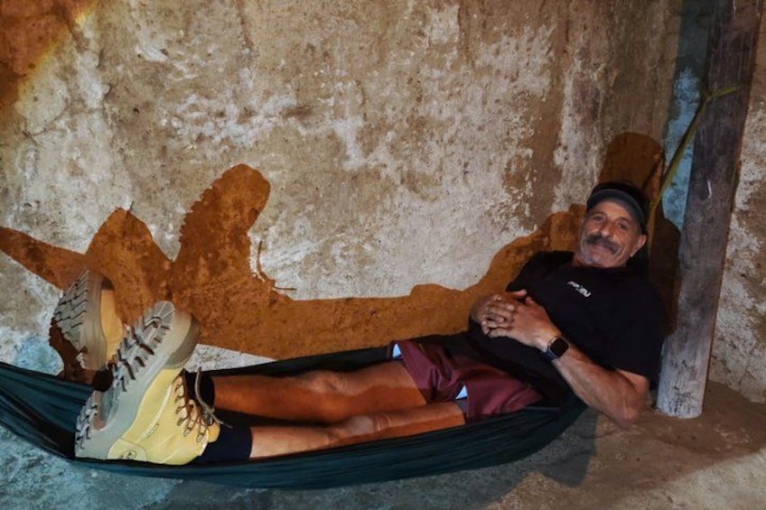 A person lying in a hammock against a rough wall. 3