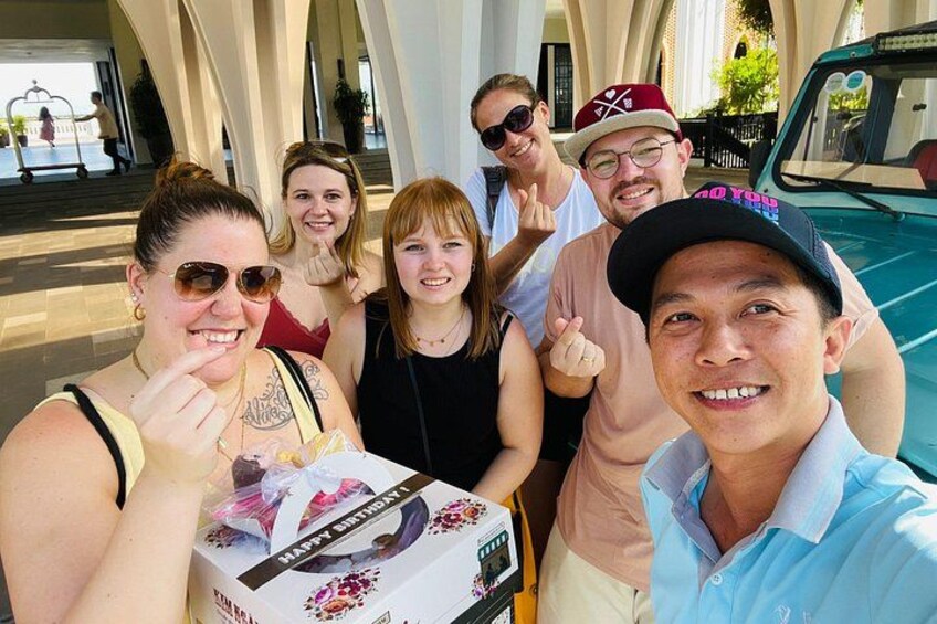 Un gruppo di persone che posano per una foto, una scatola regalo e un veicolo. 4