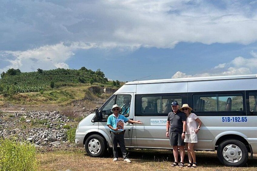 A white van parked on a grassy area with a rocky landscape in the background. 4