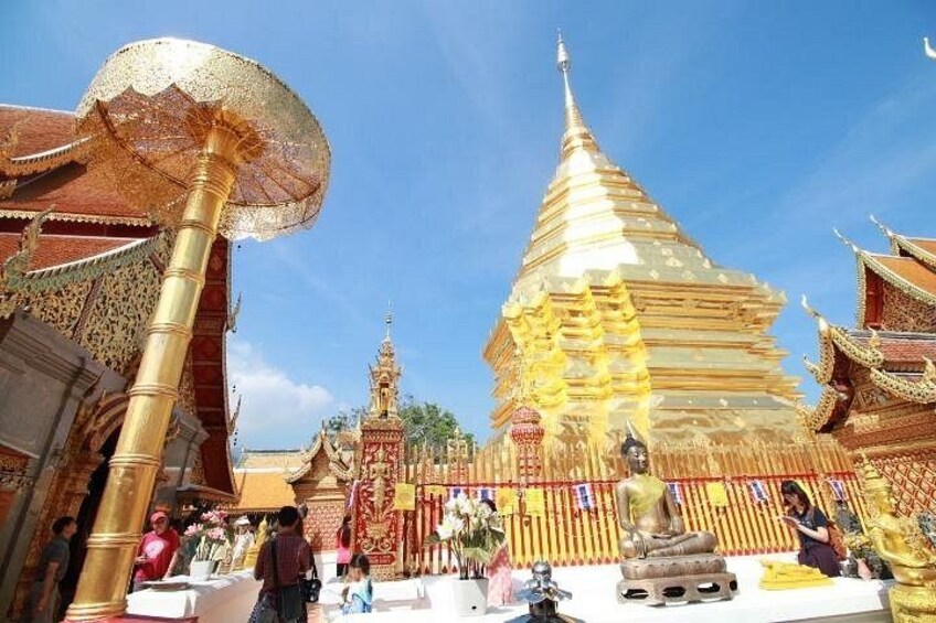 A golden stupa with intricate designs, a large umbrella-like structure, and traditional architecture. 1
