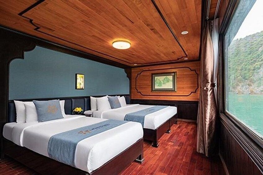 A cabin with two beds, wooden ceiling, and a window overlooking a body of water. 5