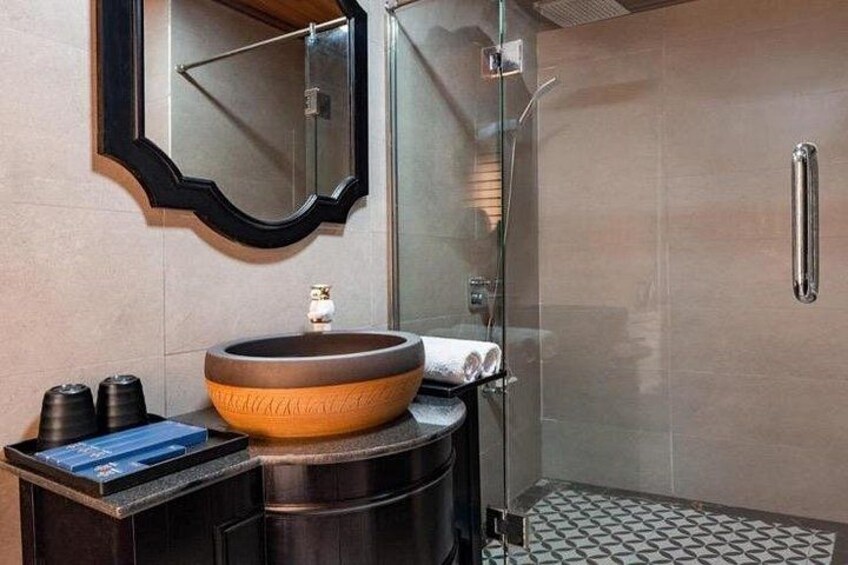 A modern bathroom with a large ceramic sink, a glass shower enclosure, and a patterned floor. 2
