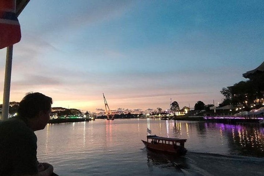 A calm river with a small boat, a distant sailboat, and a cityscape in the background. 4