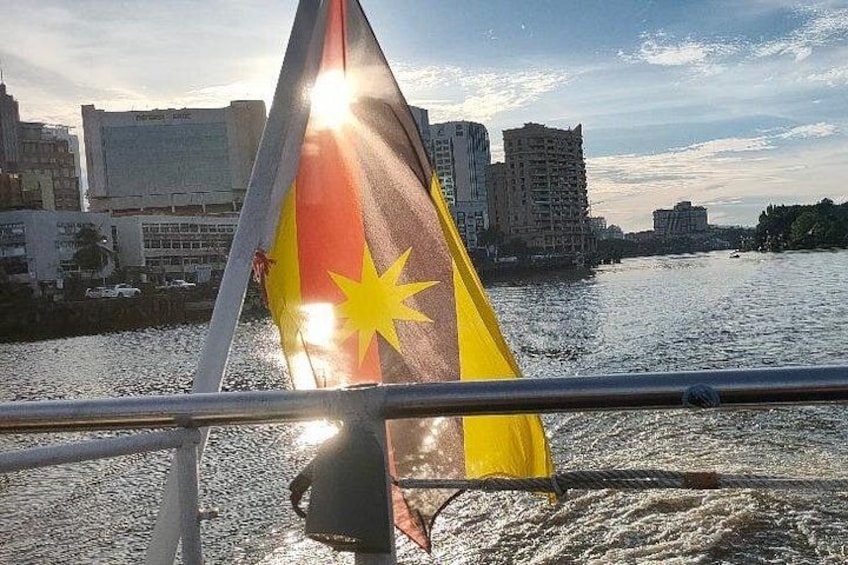 A flag on a boat with a cityscape in the background. 2