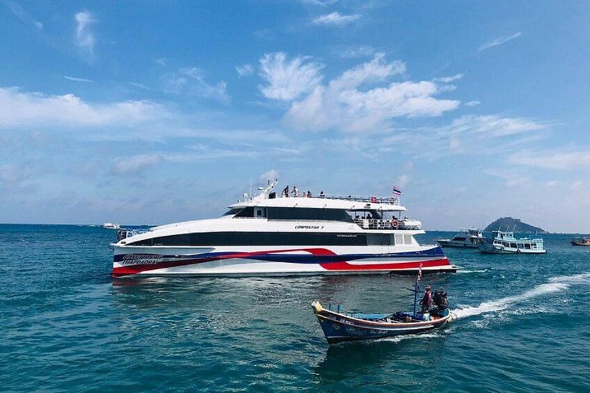 A large white yacht with red and blue stripes, a smaller boat in the foreground, and a distant island. 3