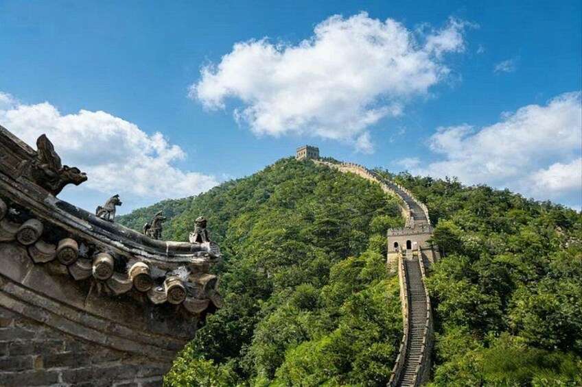 A section of the Great Wall of China, a historical landmark, winding through a lush green mountain. 3