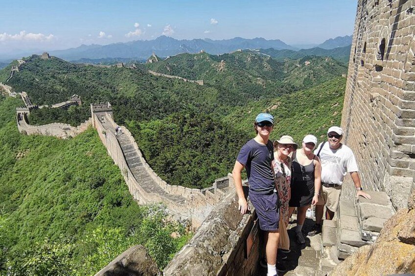 Eine Gruppe von Menschen steht auf der Chinesischen Mauer, im Hintergrund eine gebirgige Landschaft. 4
