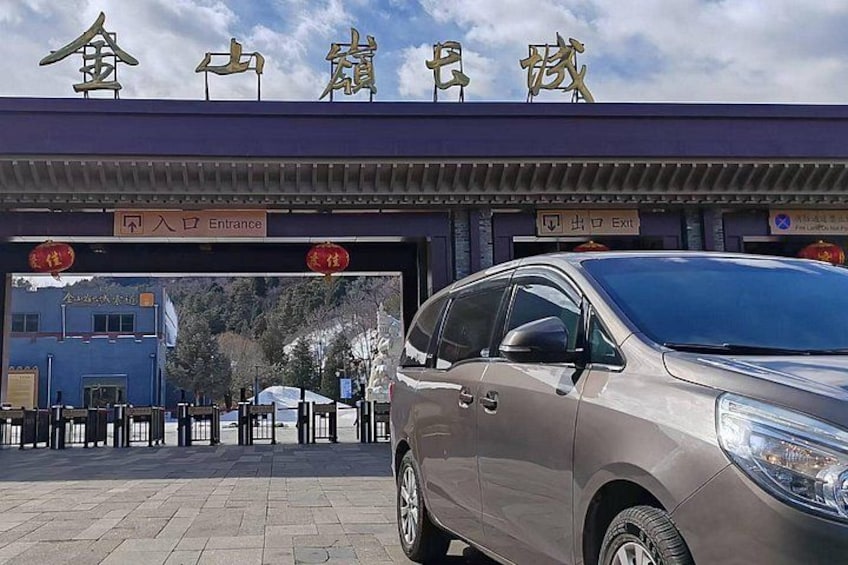 A car parked at a toll booth with a sign above reading 'Entrance' and 'Exit'. 5