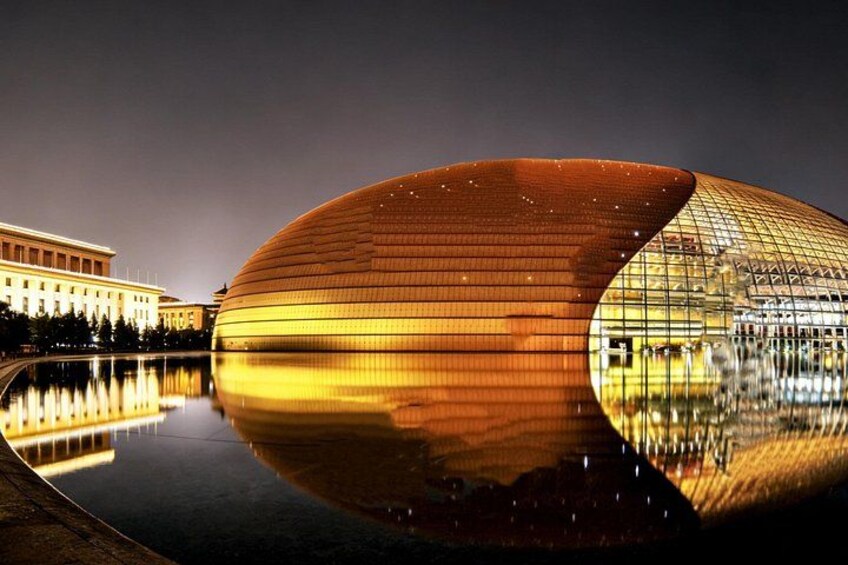 A modern building with a curved facade reflecting in a body of water, surrounded by a formal park with a classical building in the background. 4