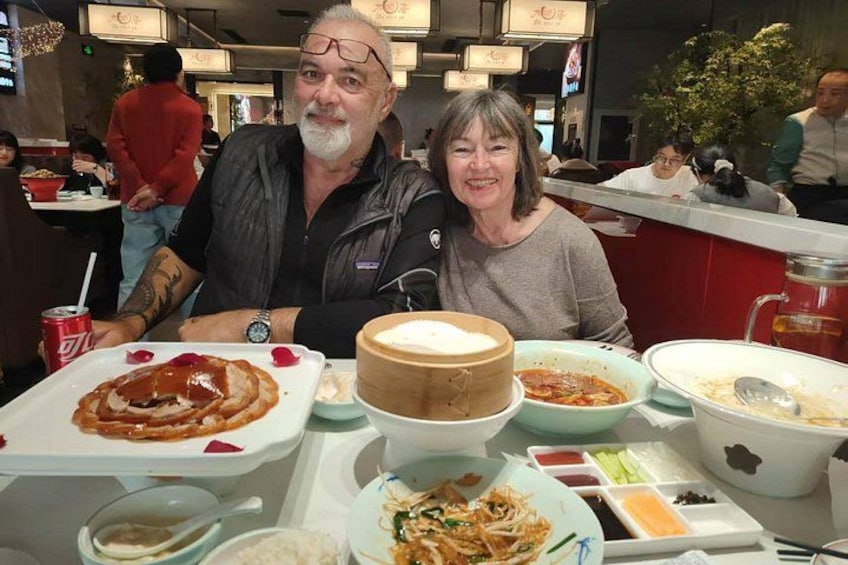 A dining table with various dishes, a person with a tattoo on their arm, and another person with a blurred face. 3