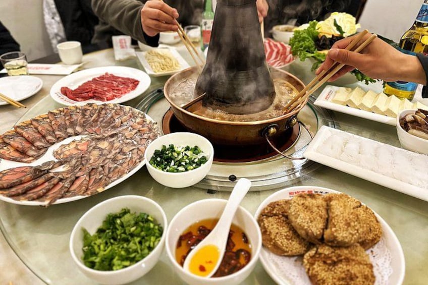 A hot pot meal with various ingredients and a steaming pot in the center. 4