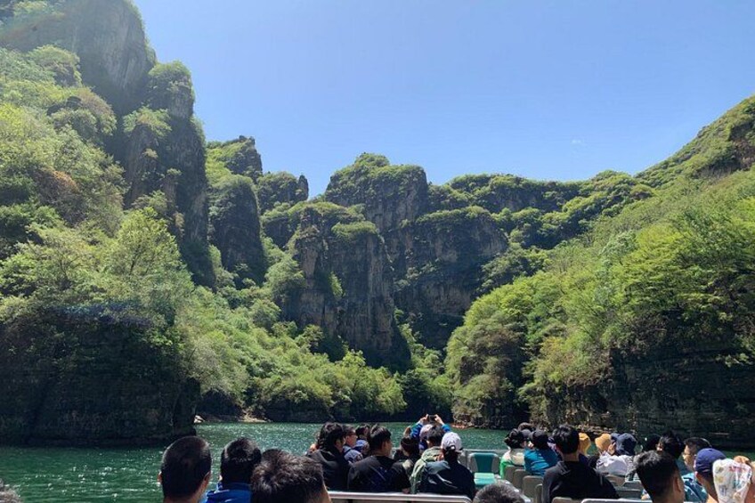 Eine Bootsfahrt, bei der Menschen Felsen und grüne Landschaften betrachten. 3