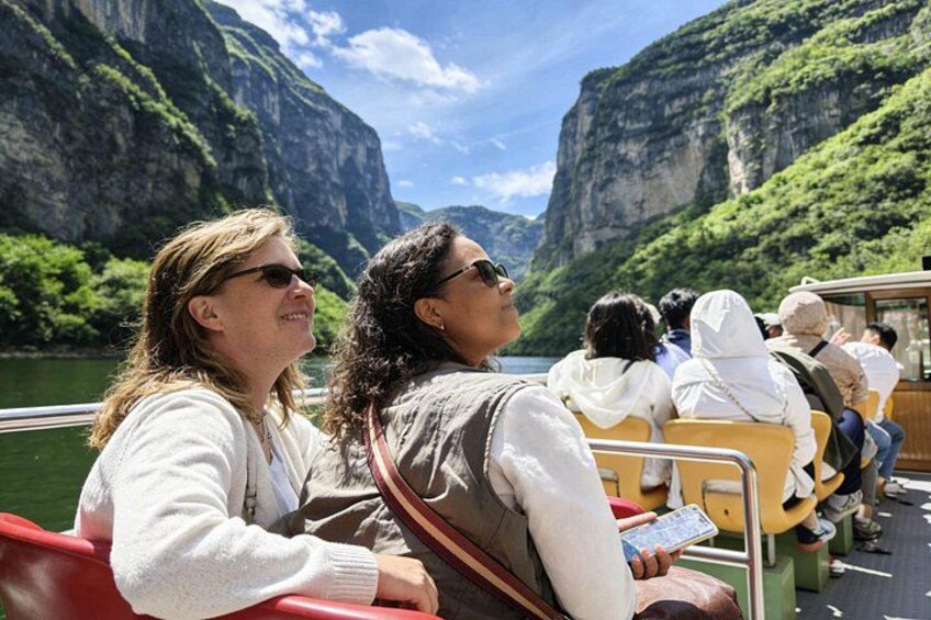 Menschen in einem Boot vor einer gebirgigen Landschaft. 1