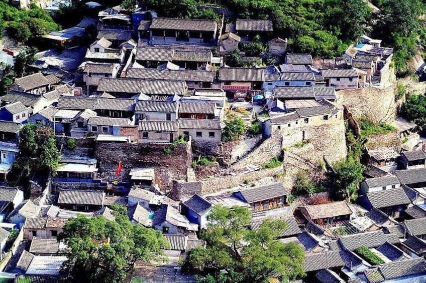 A densely packed village with traditional buildings and a stone wall. 1