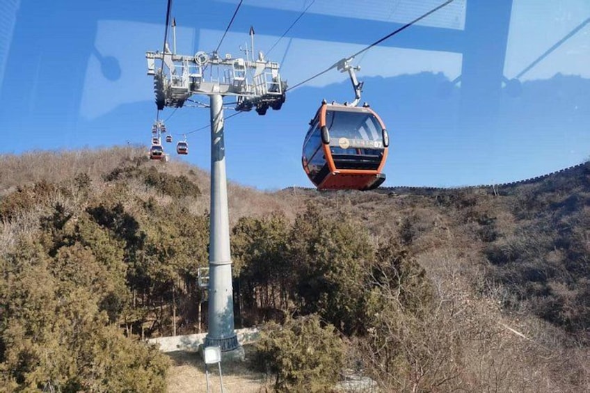 Sistema de teleférico con un telecabina en movimiento, una estación de teleférico y un paisaje montañoso. 5