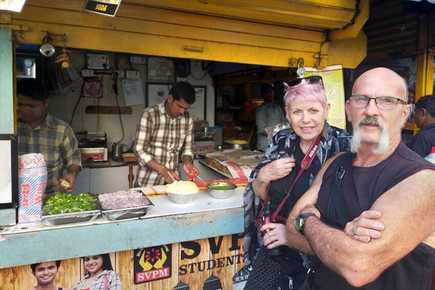 Een kraam met straatgerecht, voorzien van een geel luifel, een persoon bereidt eten, en een bord waarop 'SVPM STUDENT' staat. 3
