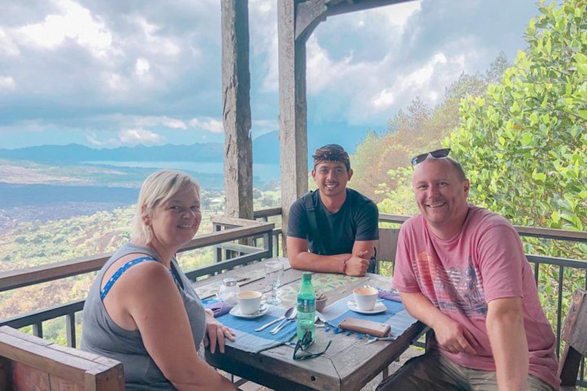 Three people sitting at a table with a scenic view of mountains and a lake. 5
