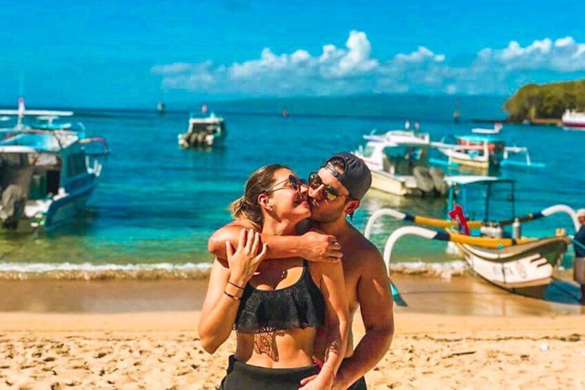 A couple embracing on a beach with boats in the background. 4