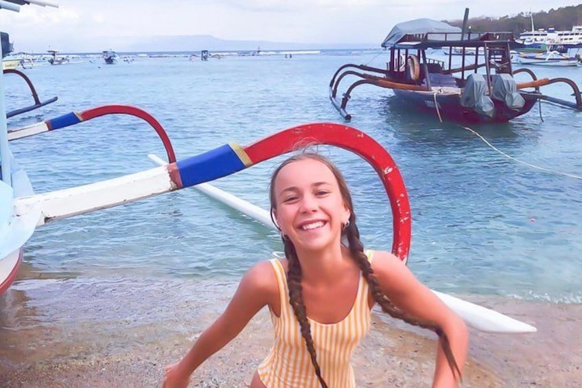 A person standing on a beach with boats in the background. 2