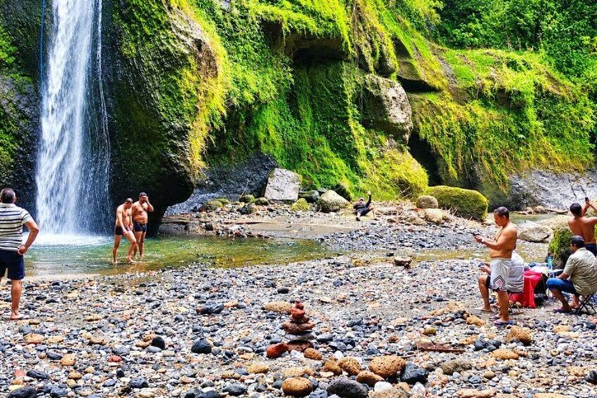 Una cascada, terreno rocoso y gente cerca del agua. 5
