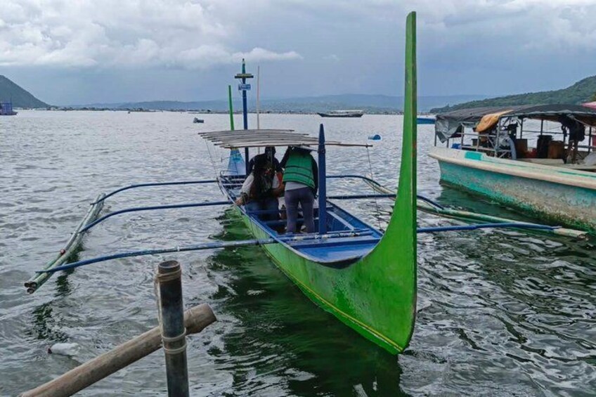Un bateau vert avec deux personnes à bord, amarré à un quai, avec d’autres bateaux en arrière-plan. 3