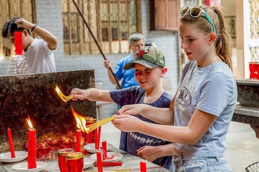 People lighting candles and incense sticks at a table. 2