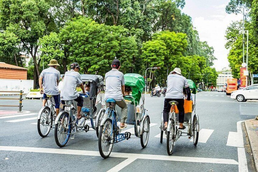 A group of people on bicycles and rickshaws on a city street. 3