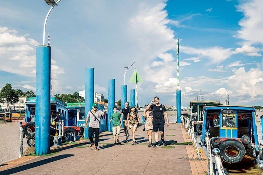 Un paseo peatonal con estructuras cilíndricas azules, una carpa verde y un vehículo azul. 2