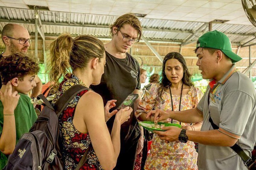 Un grupo de personas reunidas alrededor de una mesa, algunas sosteniendo platos y comiendo. 4