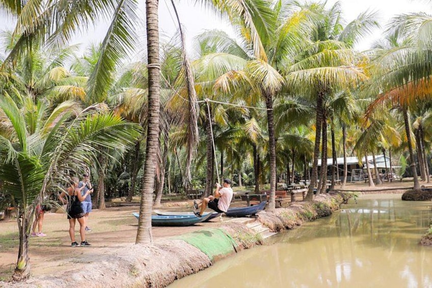 Een tropische omgeving met palmbomen, een waterpartij en mensen die buitenactiviteiten ondernemen. 4