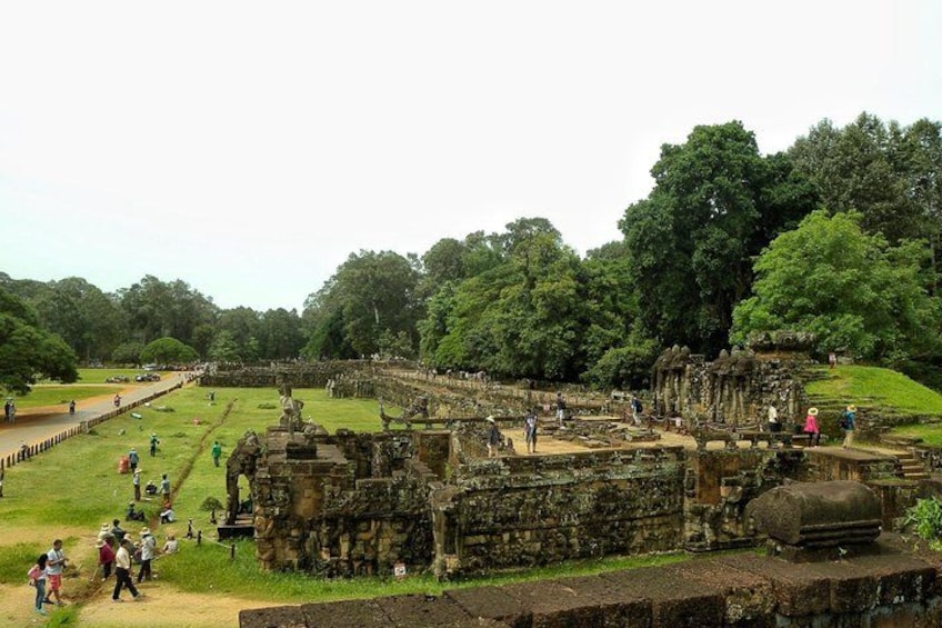 An ancient temple complex with ruins, visitors, and lush greenery. 5