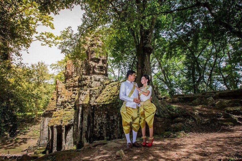 A couple standing in front of a stone structure surrounded by trees. 2