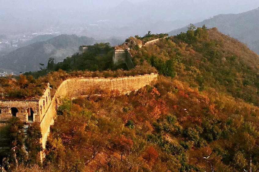 A historical wall with watchtowers, autumn foliage, and a hilly landscape. 2