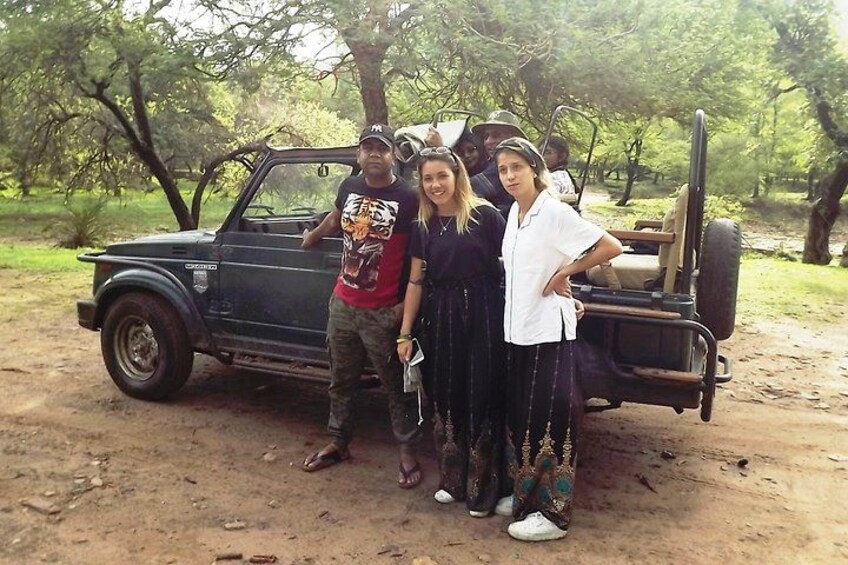 A group of people posing with a vintage car and a cart in a wooded area. 3