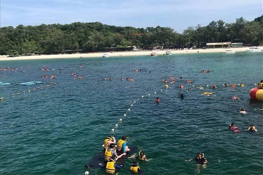 Ein Strand mit badenden Menschen und einem Boot voller Passagiere. 5