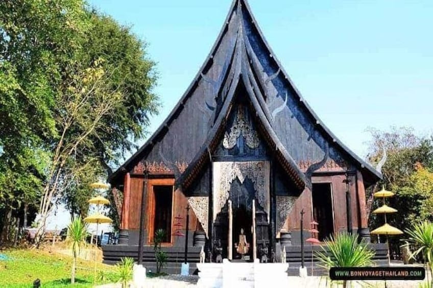 A traditional wooden structure with a pointed roof, surrounded by greenery and a clear sky. 4