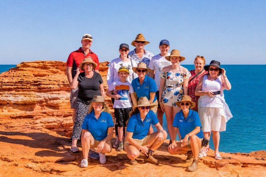 A group of people posing on a rocky outcrop by the sea. 4