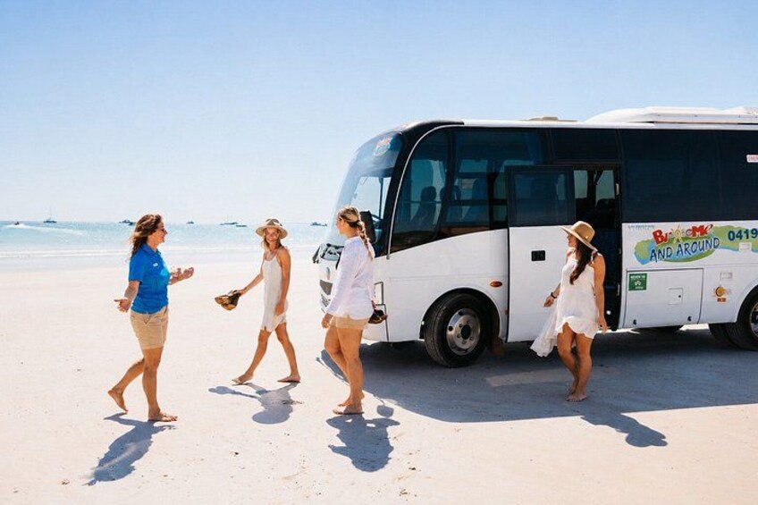 Ein Strand mit einem Bus und vier Personen, die am Strand entlanggehen. 5