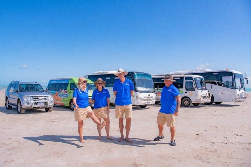 A group of people standing in front of beachside buses. 2