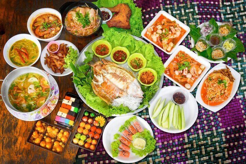 A variety of dishes including fish, vegetables, and sauces on a woven tablecloth. 2