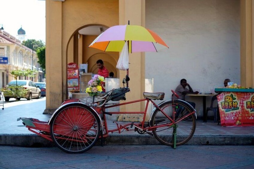 Una bicicleta roja con una cesta, estacionada en una calle con un paraguas colorido. 4